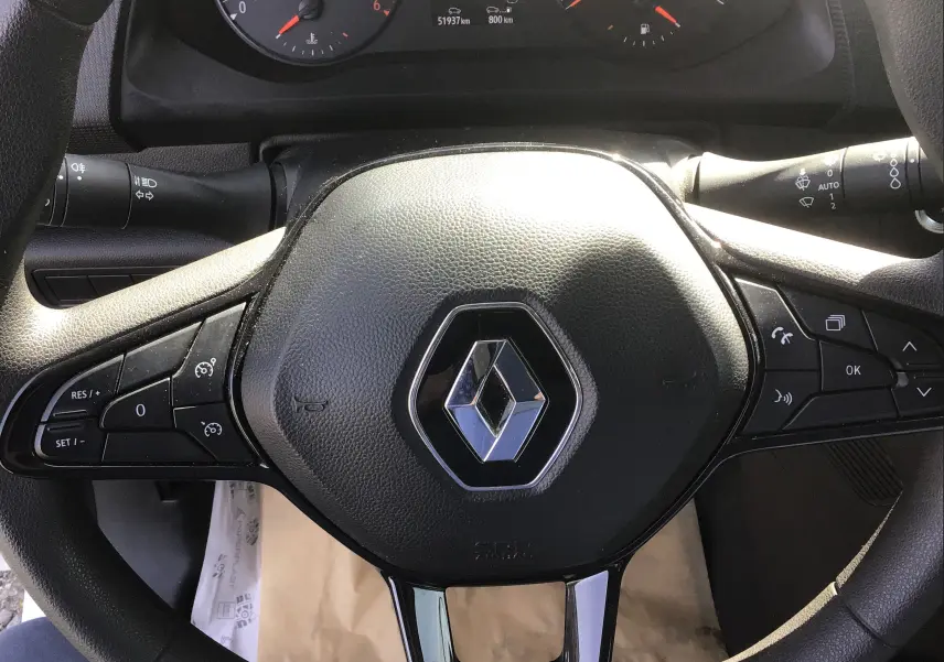 Vue rapprochée du volant noir du Renault Kangoo 2024 avec commandes intégrées et logo central chromé.