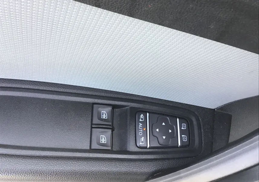 Gros plan sur les commandes de lève-vitres et réglage des rétroviseurs côté conducteur du Renault Kangoo blanc 2024.