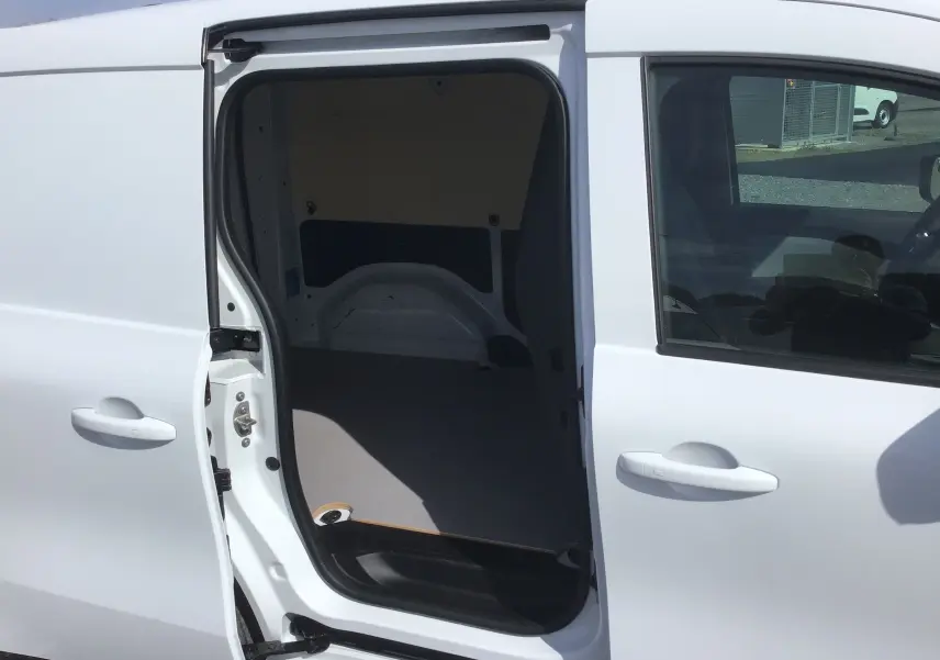 Vue latérale gauche sur le Renault Kangoo Van blanc 2024 avec porte coulissante ouverte montrant l’espace de chargement vide.