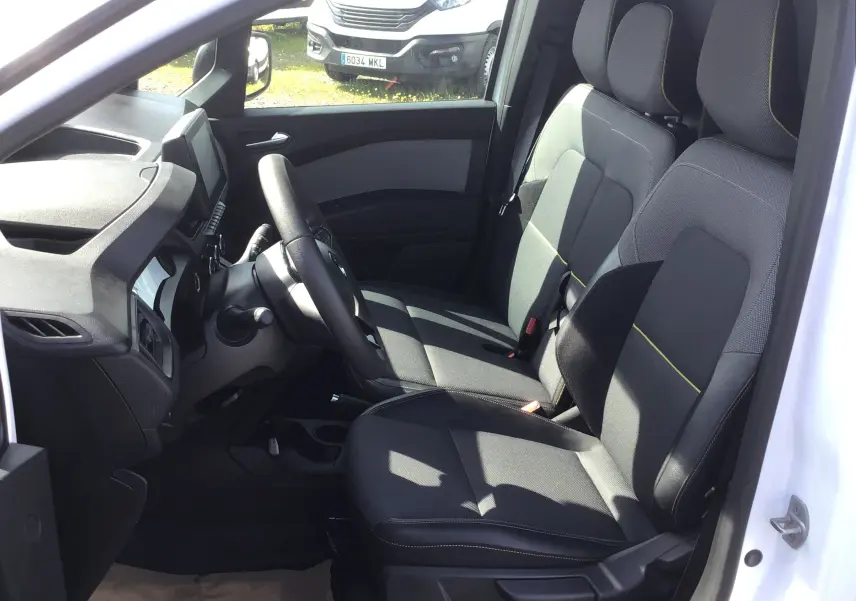 Vue intérieure côté conducteur du Renault Kangoo blanc 2024, montrant les sièges avant en tissu noir avec surpiqûres jaunes.