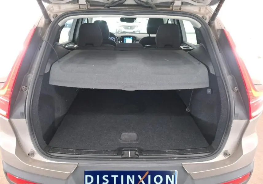 Coffre ouvert vu de l'arrière d'un Volvo XC40 marron clair 2021, avec cache-bagages en place et intérieur noir.