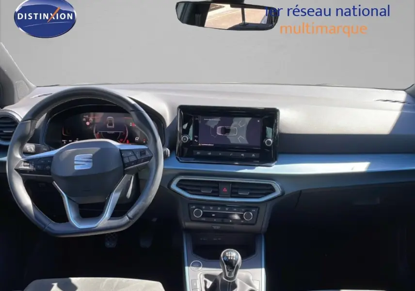 Vue intérieure frontale du tableau de bord du SEAT Arona blanc, avec volant cuir multifonction et écran tactile central.