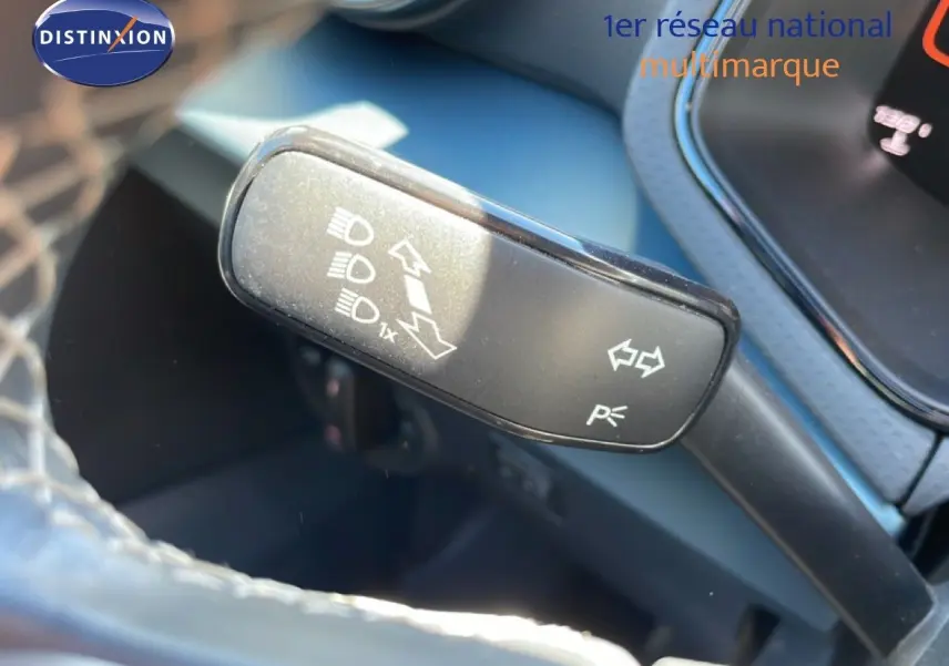 Gros plan sur la commande de clignotants et feux d’un SEAT Arona blanc toit noir, intérieur noir visible en arrière-plan.