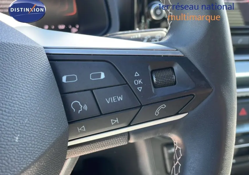 Gros plan sur les commandes multifonctions à droite du volant en cuir noir du SEAT Arona blanc toit noir, 2025.