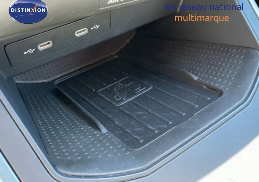 Gros plan sur le compartiment de recharge sans fil et ports USB dans l'habitacle du SEAT Arona 2025 blanc toit noir.