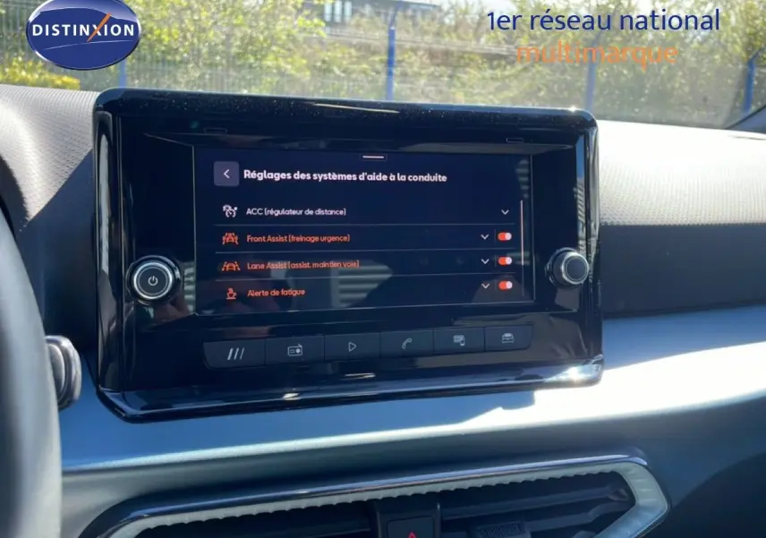 Vue intérieure centrée sur l'écran tactile du tableau de bord du SEAT Arona blanc toit noir, affichant les aides à la conduite.