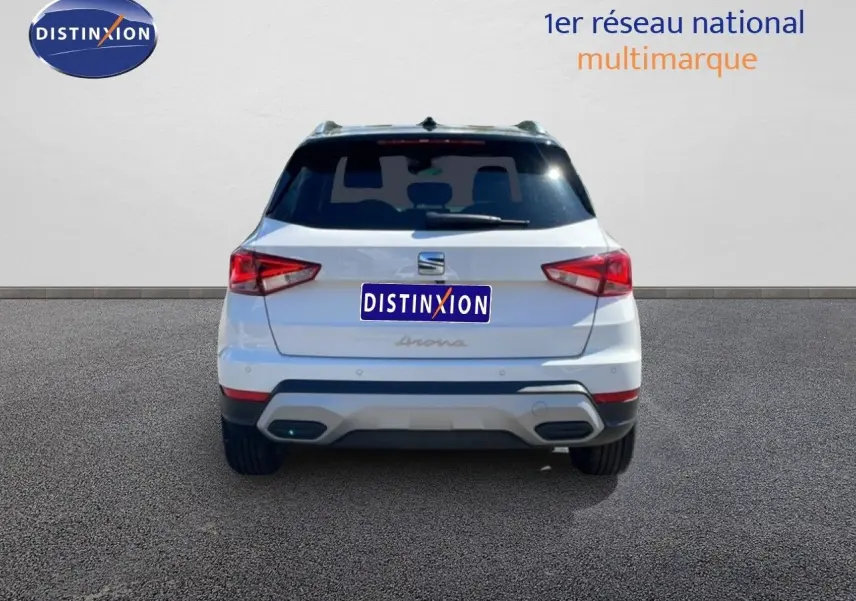 Vue arrière d'un SEAT Arona blanc avec toit noir, affichant ses feux arrière et son pare-chocs gris.