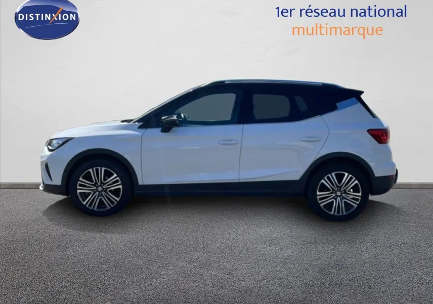 Vue de profil côté gauche d'une SEAT Arona blanche avec toit noir, roues alliage et lignes modernes, sur fond neutre.