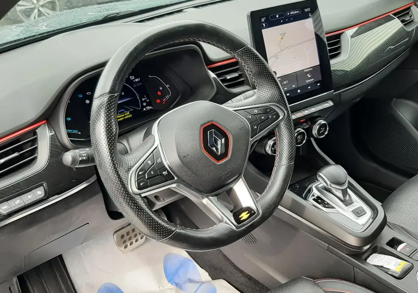 Vue intérieure côté conducteur du tableau de bord et volant noir perforé avec surpiqûres rouges du Renault Arkana E-Tech 145ch RS-Line.