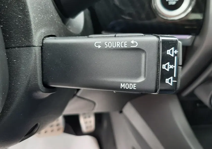 Gros plan sur la commande au volant gauche du Renault Arkana E-Tech 145ch RS-Line, avec bouton Start/Stop visible en arrière-plan.