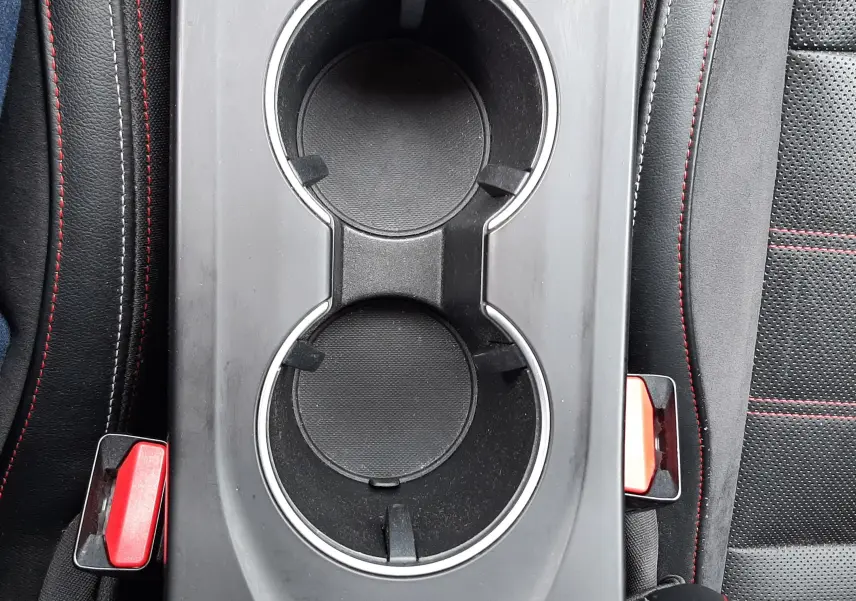 Vue plongeante sur la console centrale noire avec porte-gobelets et surpiqûres rouges des sièges du Renault Arkana E-Tech 145ch RS-Line.
