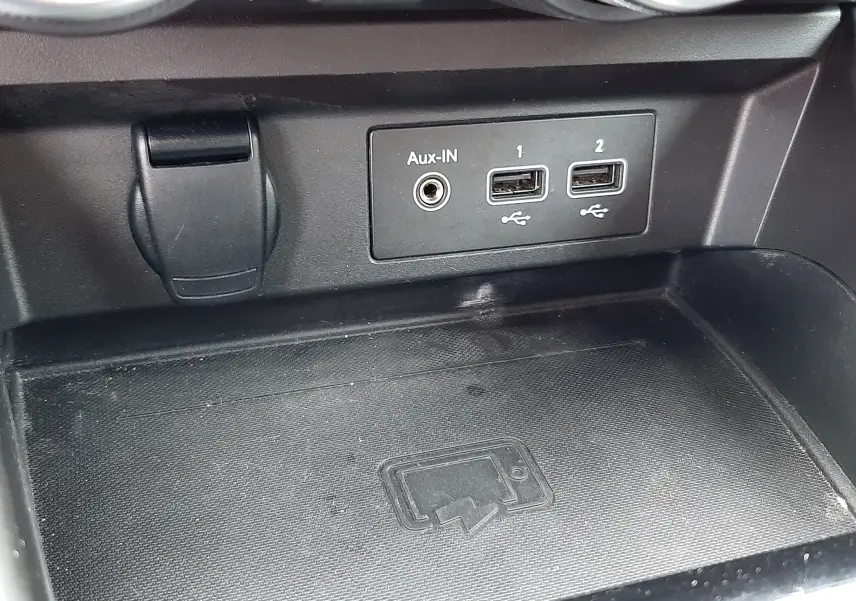Gros plan sur la console centrale du Renault Arkana E-Tech 145ch RS-Line 2021, montrant les ports USB, entrée Aux-IN et surface de recharge sans fil.
