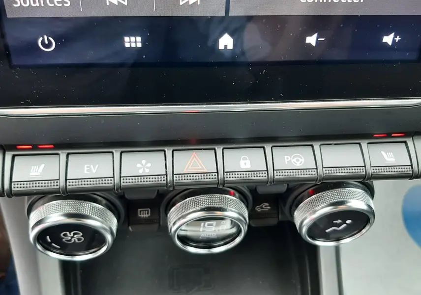 Vue rapprochée de la console centrale du Renault Arkana E-Tech bleu Zanzibar, montrant les commandes de climatisation et l’écran tactile.