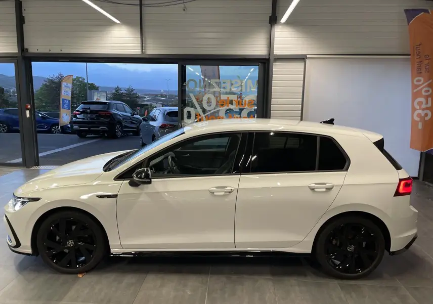 Vue de profil côté gauche d'une Volkswagen Golf blanche 2024 R-Line avec jantes noires 18 pouces Bergamo.