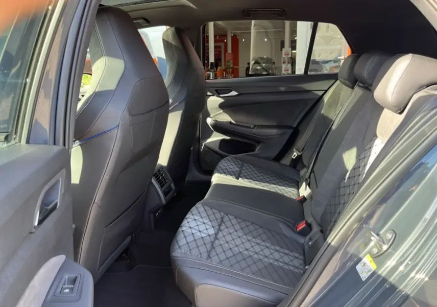 Vue intérieure arrière côté gauche de la Volkswagen Golf E-TSI 150 R-Line gris dauphin, sièges arrière en tissu et cuir avec motifs.