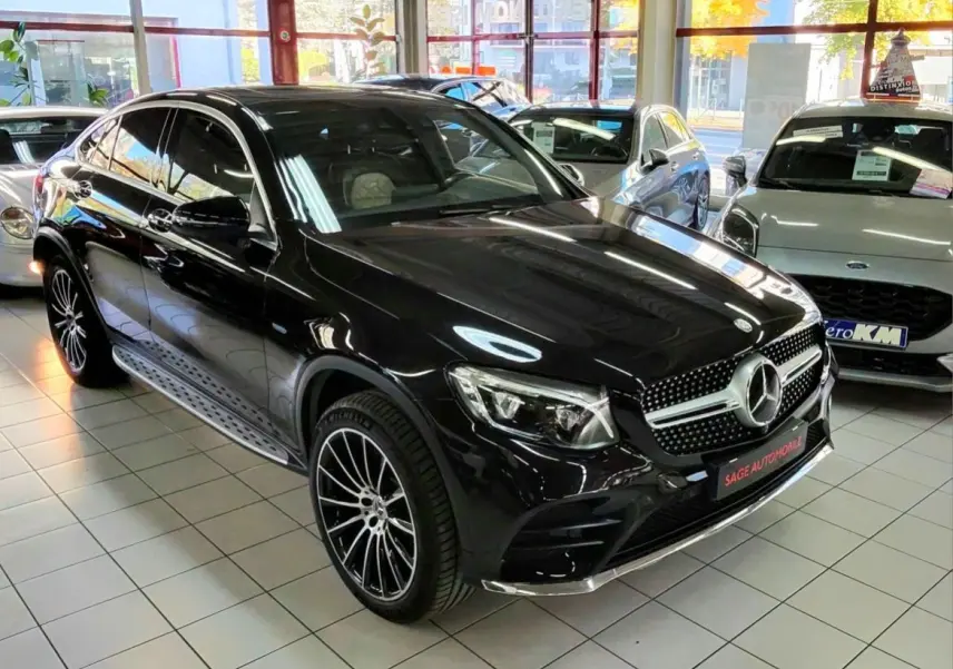 Vue 3/4 avant d'une Mercedes GLC Coupé noire brillante avec jantes sport bicolores en concession.