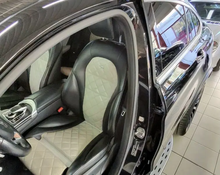 Vue côté gauche intérieur d'une Mercedes GLC 350 Sportline noire de 2017, mettant en valeur le siège avant bi-ton cuir noir et beige matelassé.