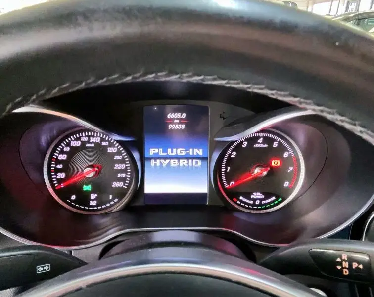 Vue intérieure du tableau de bord du Mercedes GLC 350 hybride, affichant le compteur et l'écran central "PLUG-IN HYBRID".