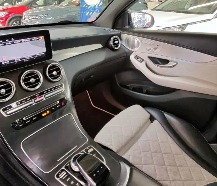 Intérieur de la Mercedes GLC 350 Sportline 2017, vue côté passager, sièges cuir blanc et tableau de bord noir avec écran central.