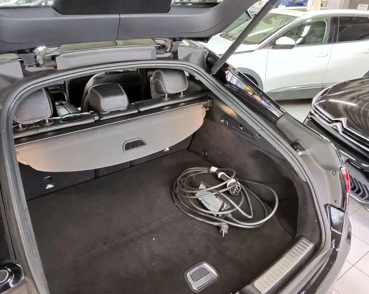 Coffre ouvert vu de l'arrière d'une Mercedes GLC Coupé noire, avec câble de recharge hybride visible à l'intérieur.