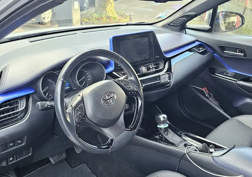 Vue intérieure côté conducteur du Toyota C-HR hybride gris 2018, avec tableau de bord et inserts bleus distinctifs.