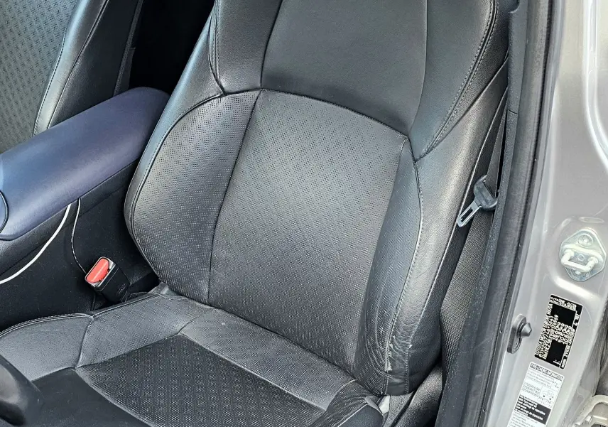 Vue intérieure côté conducteur du siège en cuir noir du Toyota C-HR hybride gris 2018, avec portière ouverte.