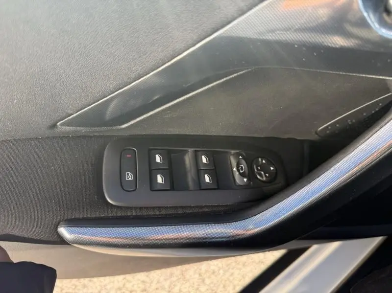Gros plan sur la commande des vitres électriques côté gauche de la porte intérieure noire du Peugeot 2008 blanc 2018.