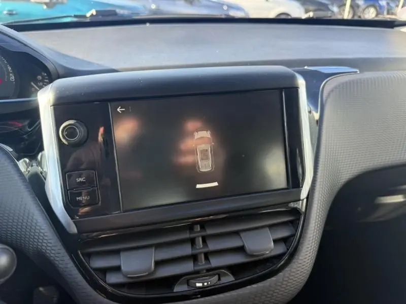 Vue rapprochée de l’écran tactile central du tableau de bord du Peugeot 2008 blanc, affichant l’aide au stationnement.