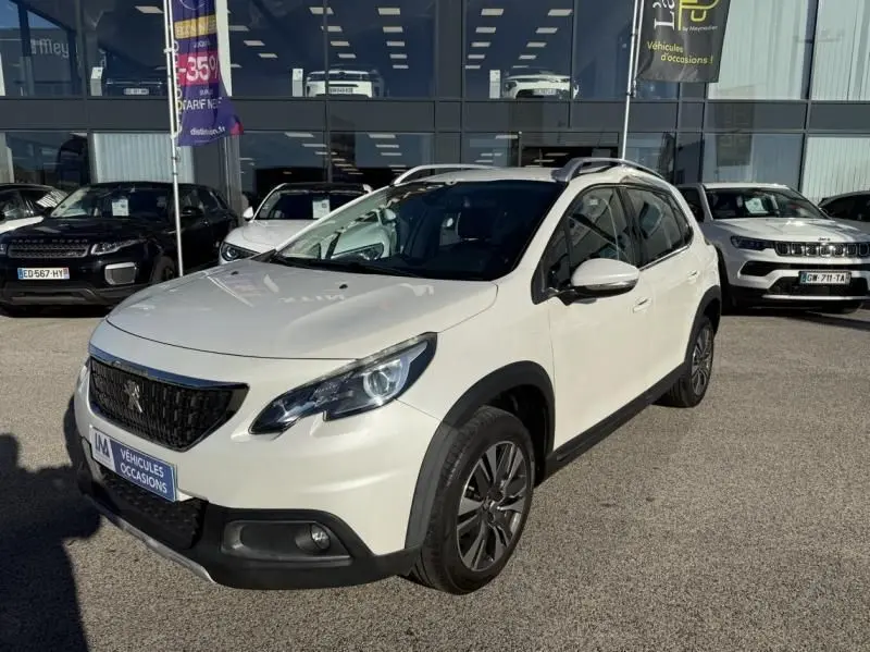 Peugeot 2008 blanc vue 3/4 avant droit, avec toit ouvrant et jantes alliage foncé, stationné devant un showroom.