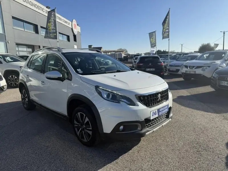 Peugeot 2008 blanc vue 3/4 avant droit, avec calandre noire et jantes alliage, stationné en extérieur sous soleil.