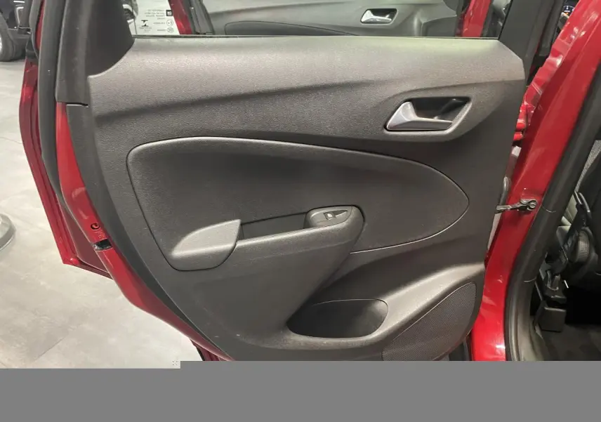 Vue rapprochée de la porte arrière droite rouge clair de l'Opel Crossland avec panneau intérieur noir et commande de vitre.