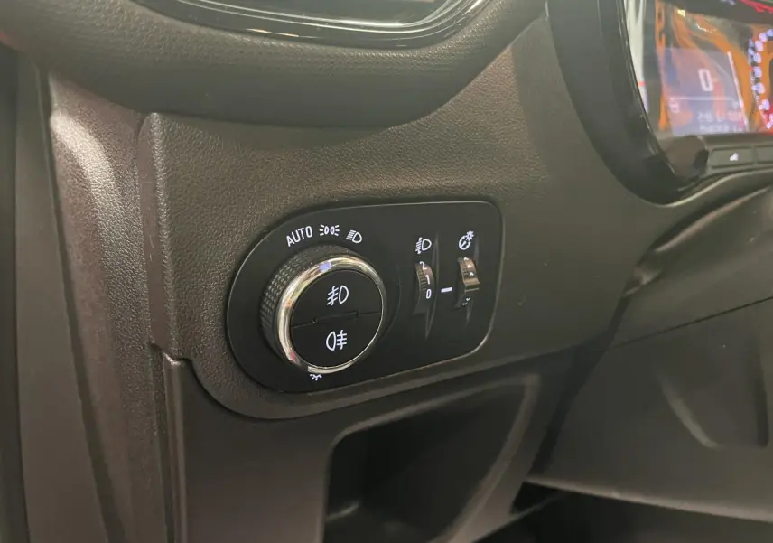 Gros plan sur le tableau de bord côté gauche de l’Opel Crossland rouge clair, montrant les commandes d’éclairage et le compteur digital.