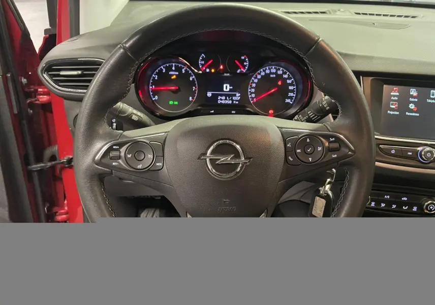 Vue intérieure centrée sur le volant en cuir multifonction de l’Opel Crossland rouge clair avec tableau de bord et écran tactile.