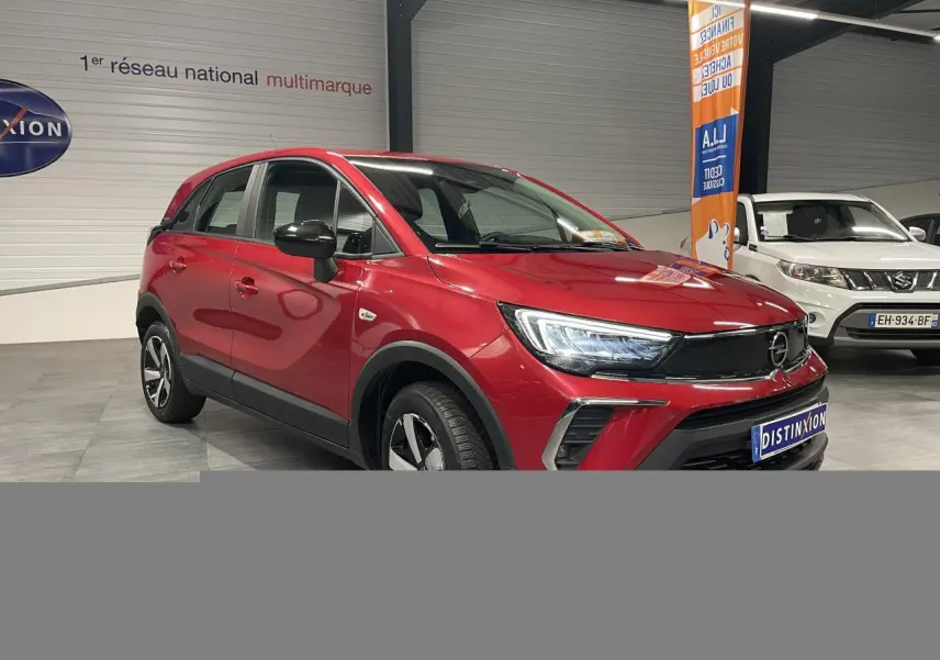Opel Crossland rouge clair en 3/4 avant droit, avec coques de rétroviseurs noires et jantes bicolores 16 pouces.