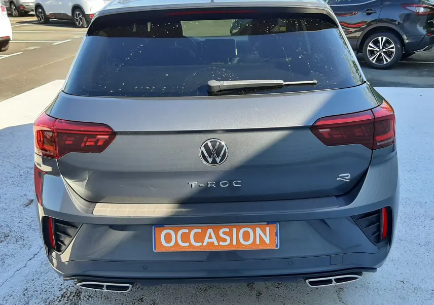 Vue arrière d'un Volkswagen T-Roc gris Indium 2024 avec badge R-Line et double sortie d'échappement rectangulaire.