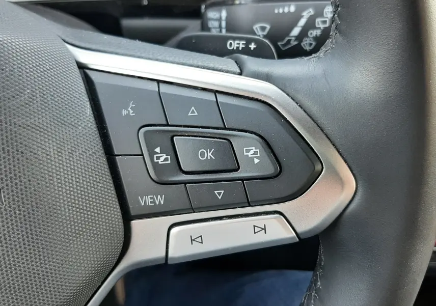 Gros plan sur les commandes multifonctions à gauche du volant du Volkswagen T-Roc gris Indium, 2024, version R-Line.