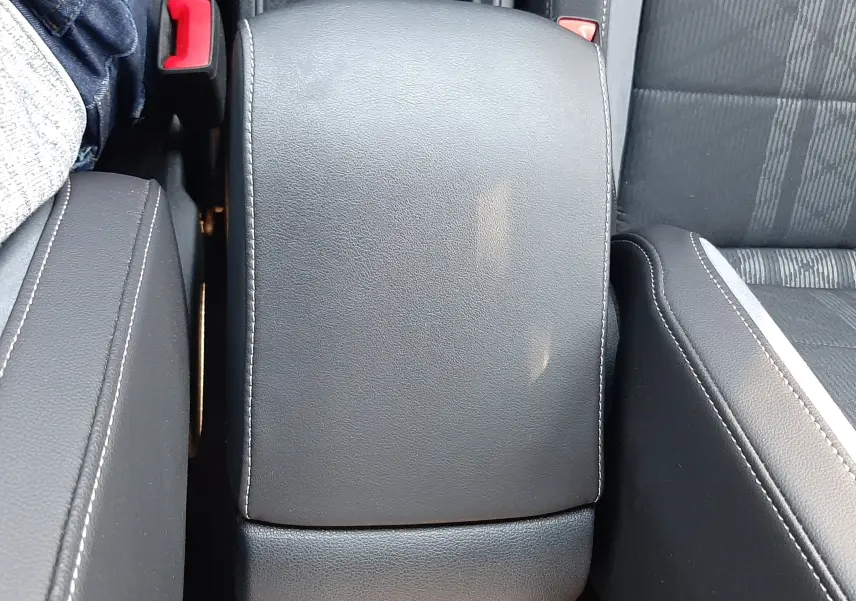 Vue rapprochée de l'accoudoir central en cuir noir avec surpiqûres blanches dans l'habitacle du Volkswagen T-Roc 2024.