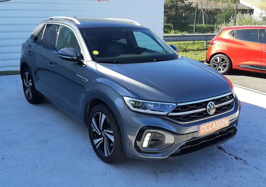Volkswagen T-Roc gris Indium en 3/4 avant droit, avec jantes alliage bicolores et calandre R-Line distinctive.