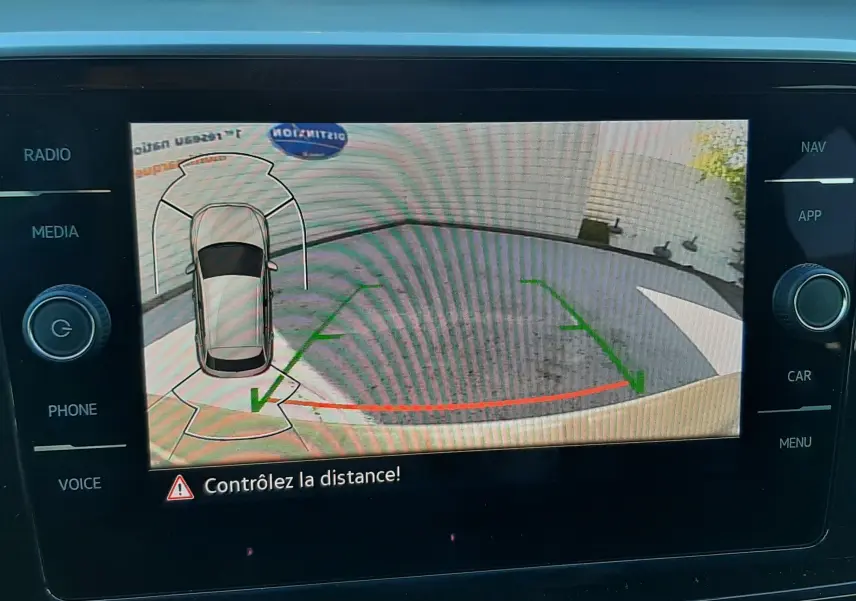 Écran de caméra de recul du Volkswagen T-Roc gris Indium, affichant les lignes de guidage et l'alerte de distance.