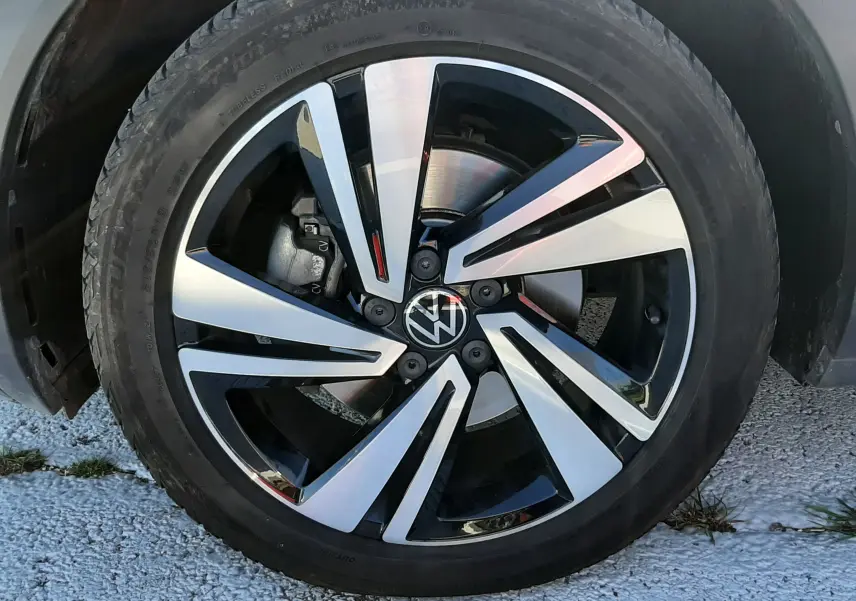 Gros plan sur la jante alliage bicolore noire et argent avec logo Volkswagen du Volkswagen T-Roc gris Indium.