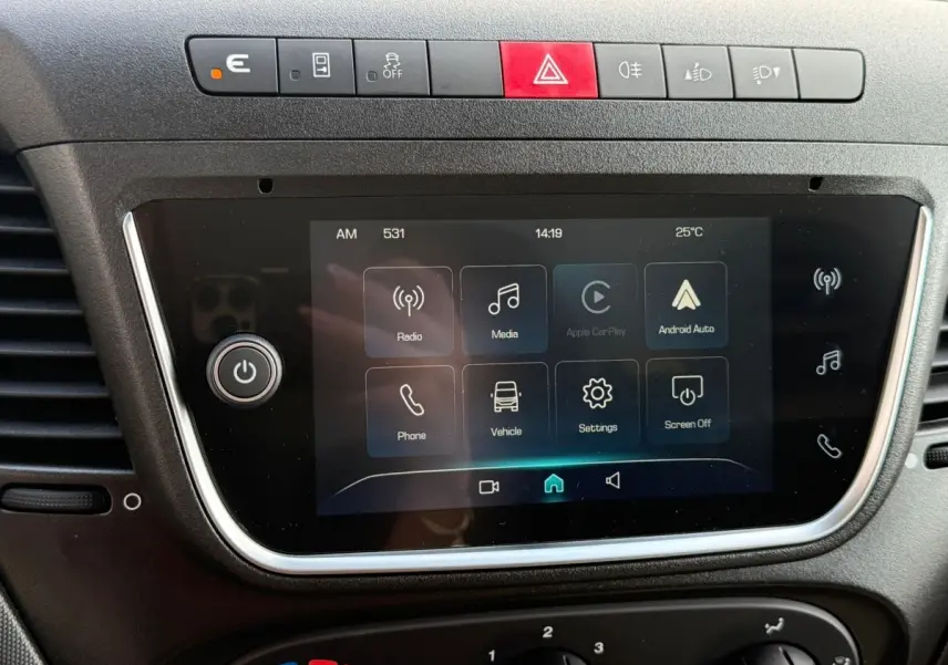 Écran tactile central avec commandes multimédia et boutons de sécurité sur le tableau de bord du Iveco Daily blanc 2026.