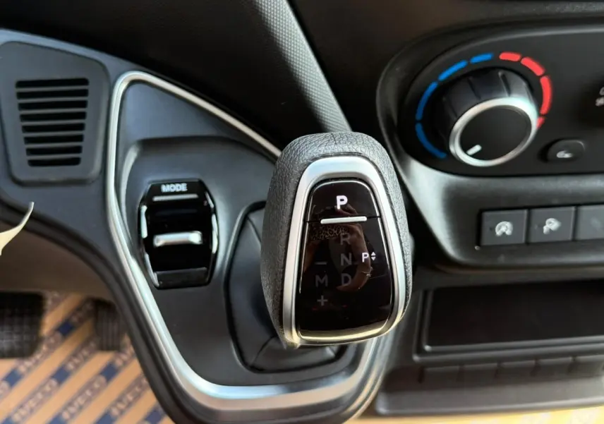 Gros plan sur le levier de vitesses automatique noir et argenté du tableau de bord du Iveco Daily blanc 2026.