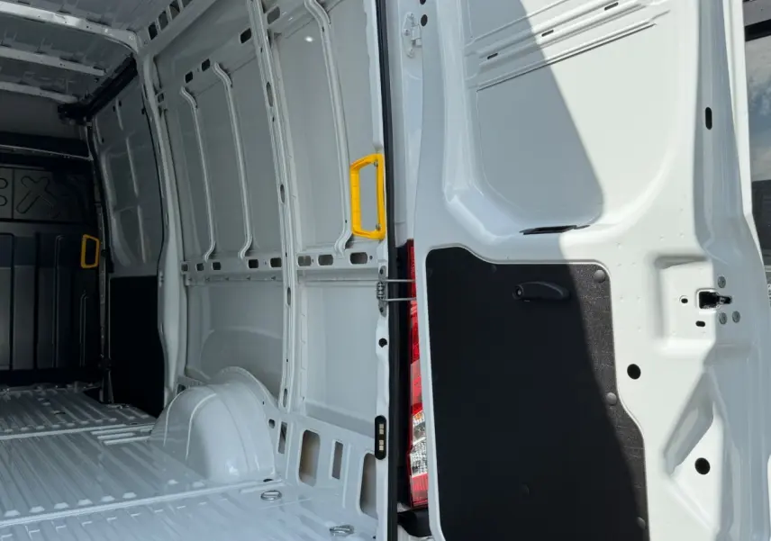 Vue intérieure arrière droite du fourgon Iveco Daily blanc 2026, montrant la zone de chargement vide avec poignée jaune.