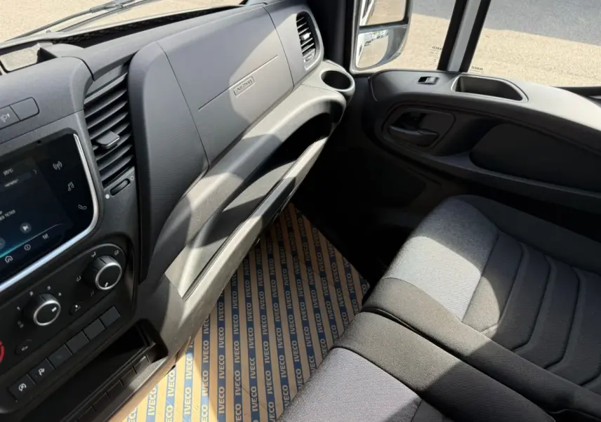 Intérieur côté passager de l’Iveco Daily 2026, tableau de bord noir et siège tissu gris en lumière naturelle.