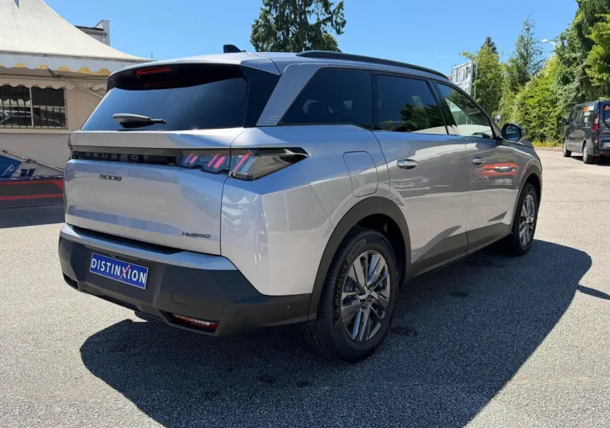 Vue 3/4 arrière droite d’un Peugeot 5008 gris clair hybride, avec feux LED et vitres teintées.