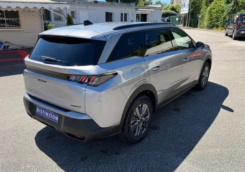 Vue 3/4 arrière droit d’un Peugeot 5008 gris clair hybride avec feux arrière LED et vitres teintées.