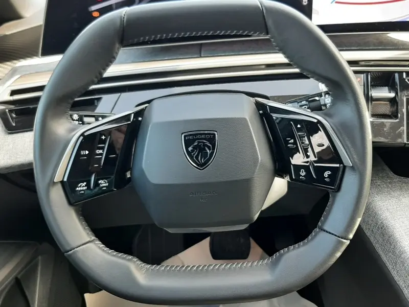 Vue rapprochée du volant cuir noir du Peugeot 5008 2025 avec commandes multifonctions et tableau de bord numérique.