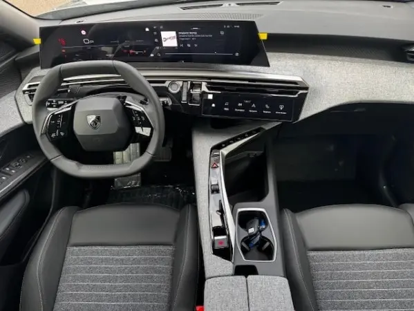 Vue intérieure frontale du tableau de bord et volant cuir noir du Peugeot 5008 gris clair 2025, avec écran tactile large.