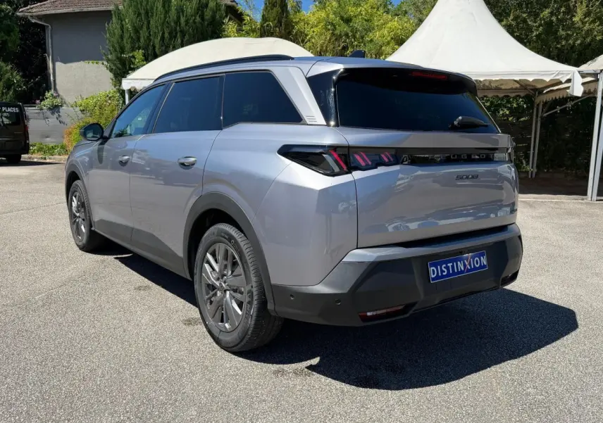 Vue 3/4 arrière droite d’un Peugeot 5008 gris clair avec feux arrière LED et vitres teintées.