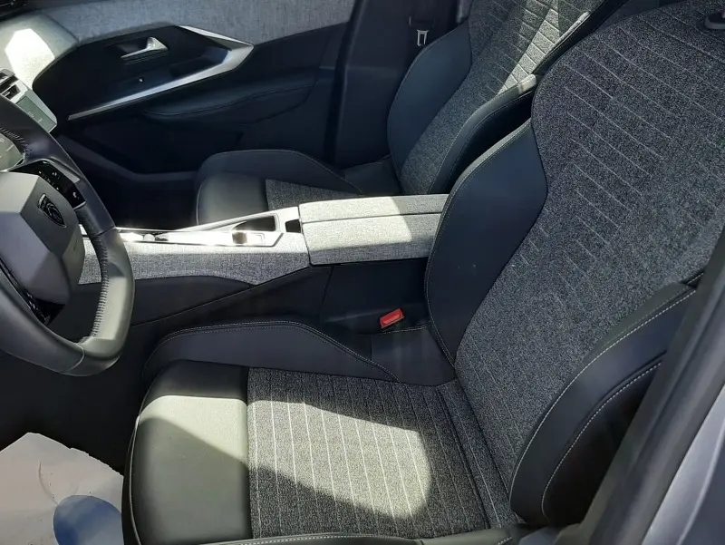 Vue intérieure côté conducteur du Peugeot 5008 2025, sièges tissu gris et cuir noir avec console centrale assortie.